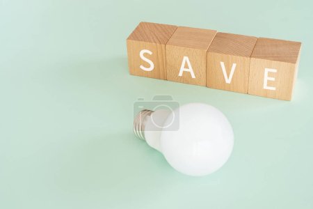Holzblöcke mit Konzepttext "SAVE" und einer Glühbirne.