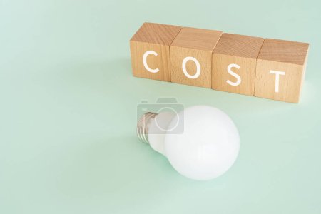 Wooden blocks with "COST" text of concept and a lightbulb.