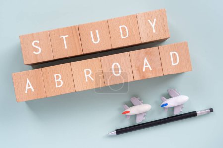 Wooden blocks with "STUDY ABROAD" text of concept, a pen, and plane toys.