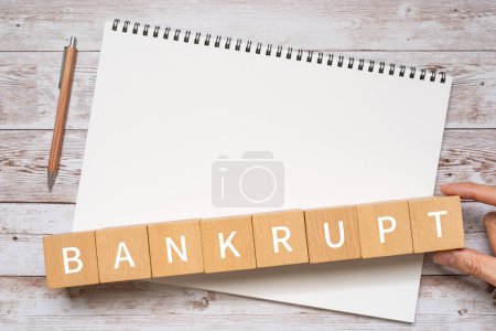 Photo for Wooden blocks with "BANKRUPT" text of concept, a pen, and a notebook. - Royalty Free Image