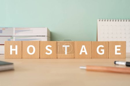 Photo for Wooden blocks with "HOSTAGE" text of concept, pens, notebooks, and books. - Royalty Free Image