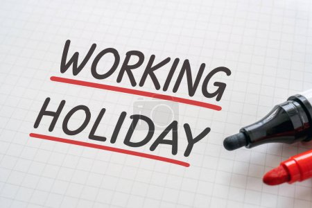 Téléchargez les photos : White paper written "WORKING HOLIDAY" with markers. - en image libre de droit