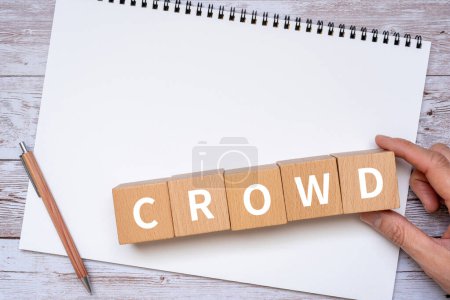 Téléchargez les photos : Blocs en bois avec "CROWD" texte de concept, un stylo, un cahier, et une main. - en image libre de droit