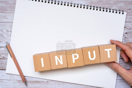 Photo for Wooden blocks with INPUT text of concept, pen, notebook and hand - Royalty Free Image
