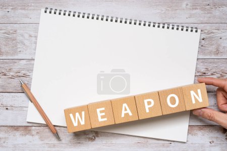 Photo for Wooden blocks with text WEAPON of concept, pen, notebook and hand - Royalty Free Image