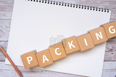 Photo for Wooden blocks with "PACKING" text of concept, a pen, and a notebook. - Royalty Free Image