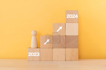 Téléchargez les photos : Blocs en bois avec "2023" et 2024 de concept et un jouet humain. - en image libre de droit