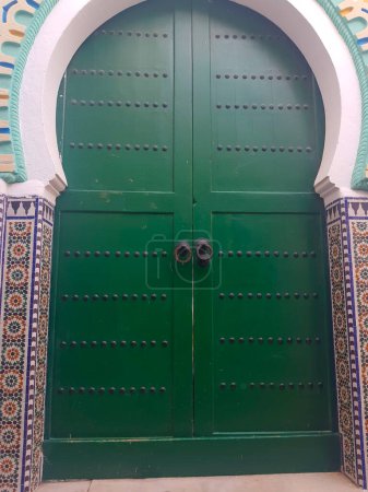 Foto de Puerta de madera verde en la ciudad vieja de Tetuán, Marruecos. La puerta es un símbolo de la rica historia de la ciudad y la belleza arquitectónica, invitando a descubrir los secretos en su interior. El color verde vibrante añade un toque de fantasía y encanto,. Como usted gaz - Imagen libre de derechos