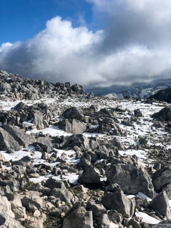 Foto de Viaje a las impresionantes alturas de la montaña, donde espera una escena de fascinante belleza. Entre las piedras escarpadas que adornan el paisaje, una manta de nieve blanca prístina crea un contraste llamativo, evocando una sensación de tranquilidad y asombro - Imagen libre de derechos