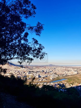 A panoramic view of the city of Tetouan, From this breathtaking vantage point, Bathed in the golden glow of the sun, the whitewashed rooftops shimmer like pearls scattered across the rolling hills.