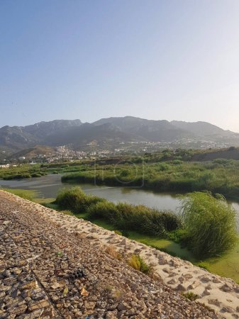 Majestätisches Tal und Berge im Rif-Gebirge Marokkos. Das Tal ist saftig und grün, mit sanften Hügeln und einem Fluss, der es durchfließt. Die Berge sind hoch und schroff