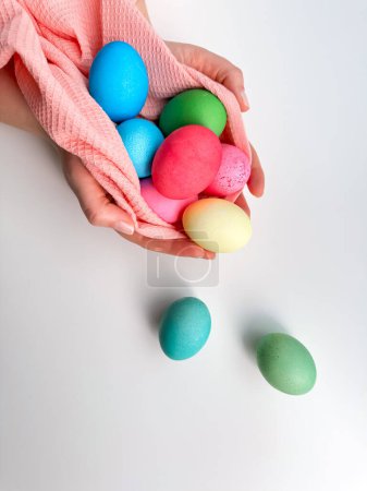 Hands cradling collection of brightly colored Easter eggs in pink fabric, evoking themes of Easter traditions, family fun, and springtime crafts. High quality photo