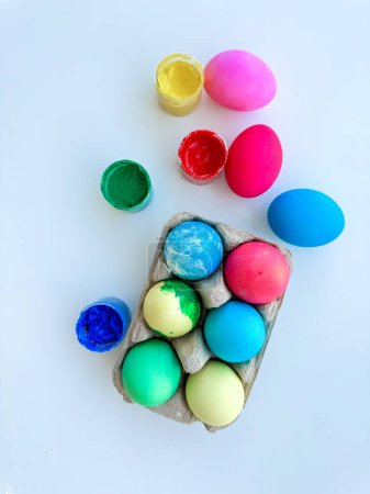 Colorful dyed Easter eggs with open paint pots on white background, depicting holiday crafts and creative family activities. High quality photo