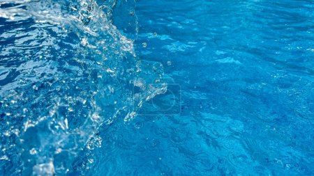 Salpicadura dinámica de fondo de agua clara creando una ola arremolinada en agua azul con gotitas suspendidas en movimiento. Concepto de agua limpia. Foto de alta calidad