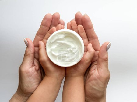 Close up of woman and childs hands holding hand cream on white background. Skincare and moisturizing concept. Design for healthcare, beauty, wellness, and family care poster. High quality photo