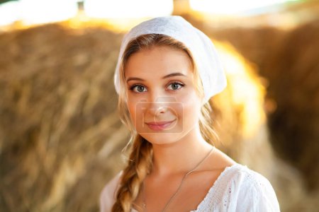 Photo for Beautiful blonde girl with braided hair in white rural clothes sitting on a straw. Farm life.Young model posing on a ranch.Warm art work. - Royalty Free Image
