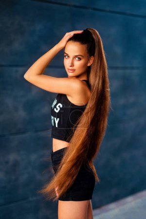 Photo for Beautiful sport girl in short blue shorts with extra long hair  on sports ground. - Royalty Free Image