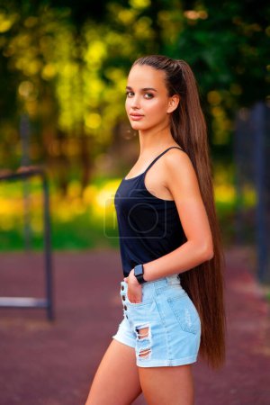 Photo for Beautiful sport girl in short blue shorts with extra long hair  on sports ground. - Royalty Free Image