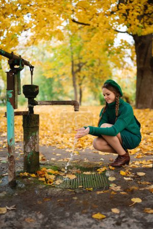 Photo for Beautiful girl in green beret and sweater with braids enjoy autumn  nature on playground. Cute teenager posing on yellow background with leaves. - Royalty Free Image