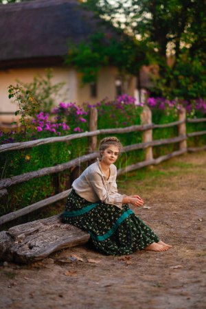 Téléchargez les photos : Belle fille blonde tressée en robe longue rurale posant dans un village. Jolie jeune modèle dans l'art de la campagne photo. - en image libre de droit