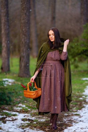 Photo for Close up portrait of Amazing fairytale princess in elven green cape and vintage dress standing in winter forest with red berries. Warm art work with queen elegant vintage lady. - Royalty Free Image