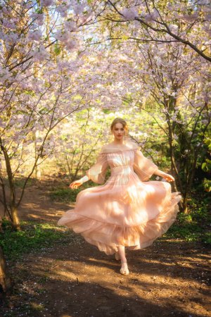 Téléchargez les photos : Belle fille en robe vintage rose debout près de fleurs colorées. Oeuvre d'art de femme romantique. Jolie modèle de tendresse posant dans le parc de fleurs. - en image libre de droit