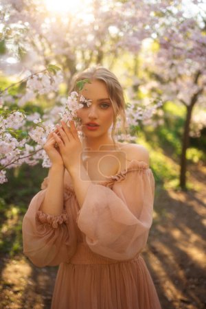 Beautiful  girl in pink vintage dress standing near colorful flowers. Art work of romantic woman .Pretty tenderness model posing  in blossom park.