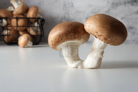 Photo for Two brown cap champignons on the table against the background of a basket with mushrooms close-up - Royalty Free Image