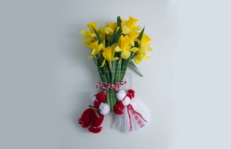 Bouquet of yellow daffodils tied with red-white martenitsa, martisor on white background copy space