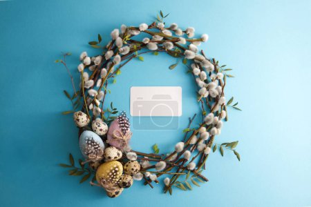 Photo for Spring willow wreath decorated with easter eggs on a blue background copy space - Royalty Free Image