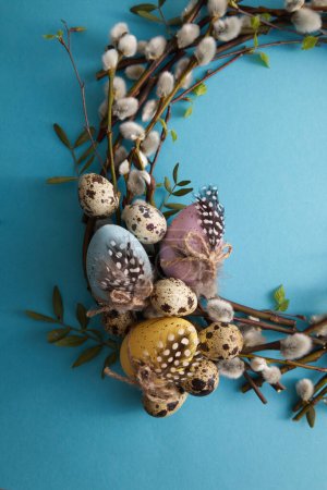 Photo for Spring willow wreath decorated with easter eggs on a blue background copy space - Royalty Free Image