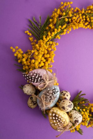 Photo for Wreath of mimosa flowers with easter eggs on purple background. High quality photo - Royalty Free Image