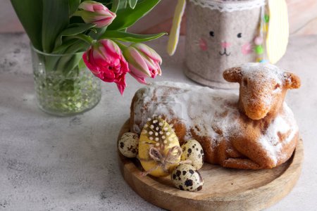 Easter cake in the shape of a lamb with Easter eggs and spring flowers on the table close up