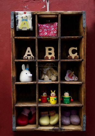 Photo for Wooden shelf with handmade toys and empty template slots on red wall. High quality photo - Royalty Free Image