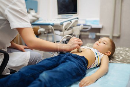Un niño se somete a un ultrasonido en la clínica. médico haciendo ecografía de cavidad abdominal para niños