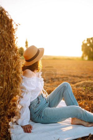 Photo for Beautiful woman near haystack at sunset. Nature, vacation, relax and lifestyle. - Royalty Free Image