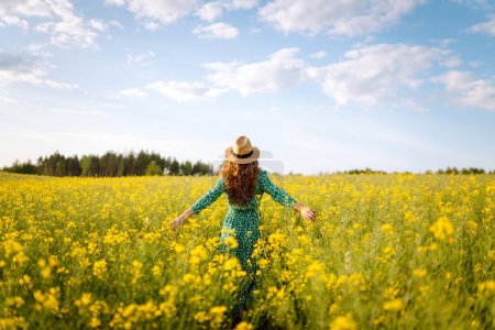 Photo for Young woman walking flowering field gently touch yellow flowers. Nature, vacation, relax and lifestyle. Summer landscape. - Royalty Free Image