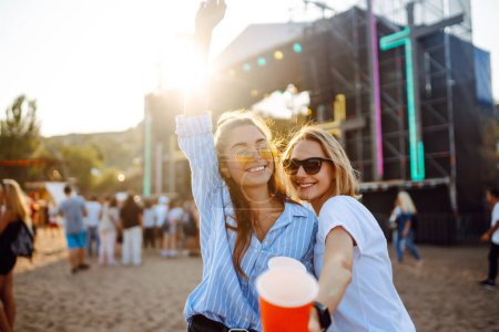 Téléchargez les photos : Joyeux deux jeunes copines s'amusent avec de la bière à la fête de la plage. Heureuses deux femmes profitent du week-end au festival de musique. Le concept d'amitié, vacances, week-end. - en image libre de droit