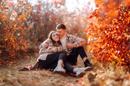 Photo for Happy and young couple walks in a beautiful autumn park, enjoys the beautiful weather. Pregnant married couple resting together in nature. Vacation, lifestyle concept. - Royalty Free Image