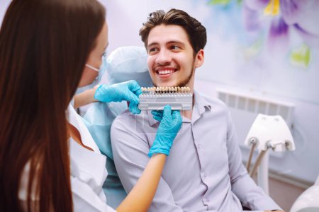 Photo for Smiling young man in the dentist's chair. A man in dentistry during a dental procedure. Healthy smile. Review of dental caries prevention. - Royalty Free Image
