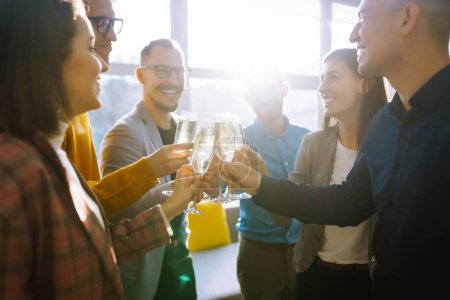 Colegas de la oficina celebran el acuerdo concluido con el champán y el vino espumoso. Un grupo de personas con copas de champán divirtiéndose, relajándose en la oficina. Concepto de trabajo, vacaciones.