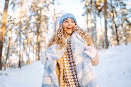 Téléchargez les photos : La jeune femme profite d'une belle journée d'hiver dans la forêt. Elle marche et aime la neige. Heure d'hiver. Le froid. Vacances, repos, concept de voyage. - en image libre de droit