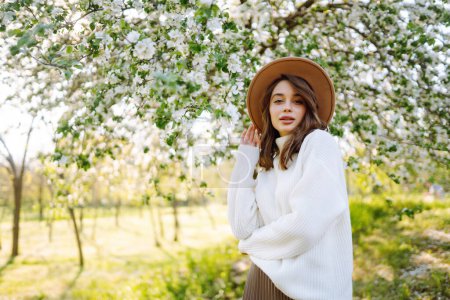 Mujer joven disfrutando del aroma en el floreciente jardín de primavera. El concepto de juventud, amor, moda, turismo y estilo de vida