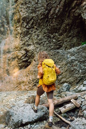 Foto de Viaja mujer joven caminando en el cañón con musgo sobre rocas después de hacer senderismo. Viajando a través de lugares escénicos. Viaje, trekking. Concepto de naturaleza. - Imagen libre de derechos
