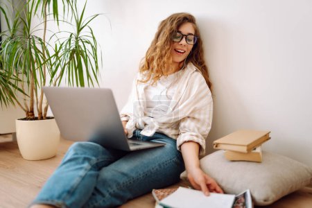 Young woman sit at home, using laptop computer, listening music with earphones. Freelance, online course. Shopping online. 