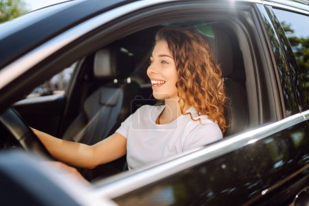 Téléchargez les photos : Une conductrice. Portrait de jeune femme conduit une voiture et souriant. Voyages en automobile. - en image libre de droit