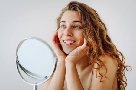 Retrato de una joven con problemas de piel se ve en el espejo. Espinillas en la cara. Cuidado facial de la piel. Problema del acné.