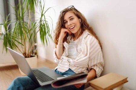 Schöne Frau benutzt Laptop zu Hause, Happy Girl chatscht mit Freunden in sozialen Netzwerken, verbringt faules Wochenende, schaut einen Film, kauft online, schreibt E-Mails. Freiberuflicher Online-Kurs.