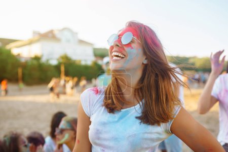 Téléchargez les photos : Femme heureuse couverte de poudre colorée arc-en-ciel célébrant holi festival de couleur. Jeune femme s'amusant avec de la poudre colorée à l'extérieur. Fête à la plage. Vacances traditionnelles indiennes. - en image libre de droit