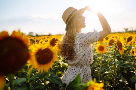 Téléchargez les photos : Belle femme posant dans un champ de tournesols. Mode, nature, voyage et vacances concept. - en image libre de droit